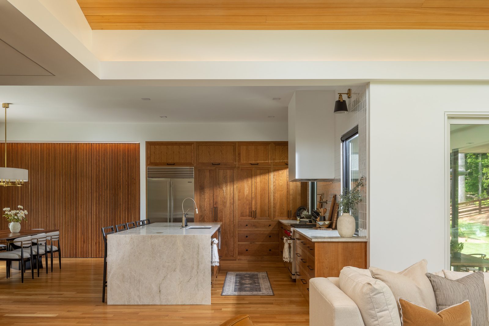 Kitchen with walnut cabinetry and marble waterfall island — The Ortiz Home, custom home built by Ironwood Construction Group in Sugar Hill, Georgia